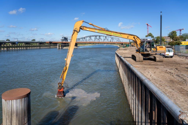 Grote kraan haalt vanaf de kant grote stukken uit het water