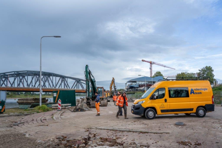 De gele bus van Archeologie staat op de kade